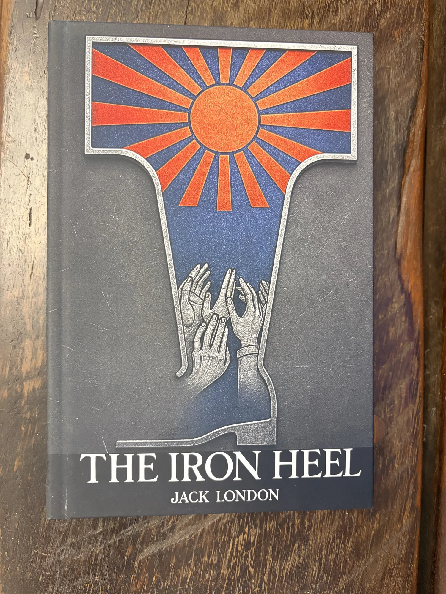 A physical copy of The Iron Heel on a wooden surface.
